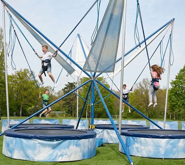 Kinderen springen hoog in de lucht op een bungee trampoline attractie tijdens een evenement in de buitenlucht.